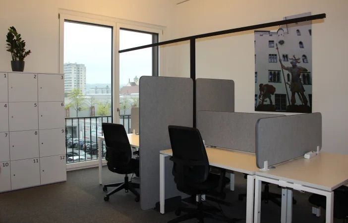 Arbeitsplätze mit Sichtschutz, Bürostühlen und Fensterfront