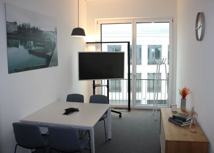 Besprechungsraum mit Konferenztisch, Bildschirm, Fensterfront und Wandbild